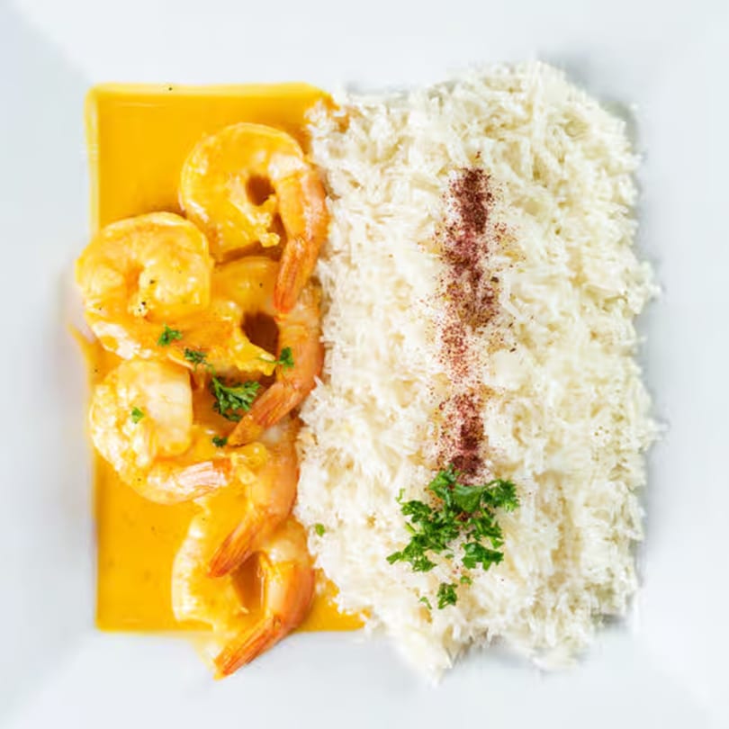 Jasmine Grill's shrimp in yellow sauce with white rice, garnished with parsley and spices.